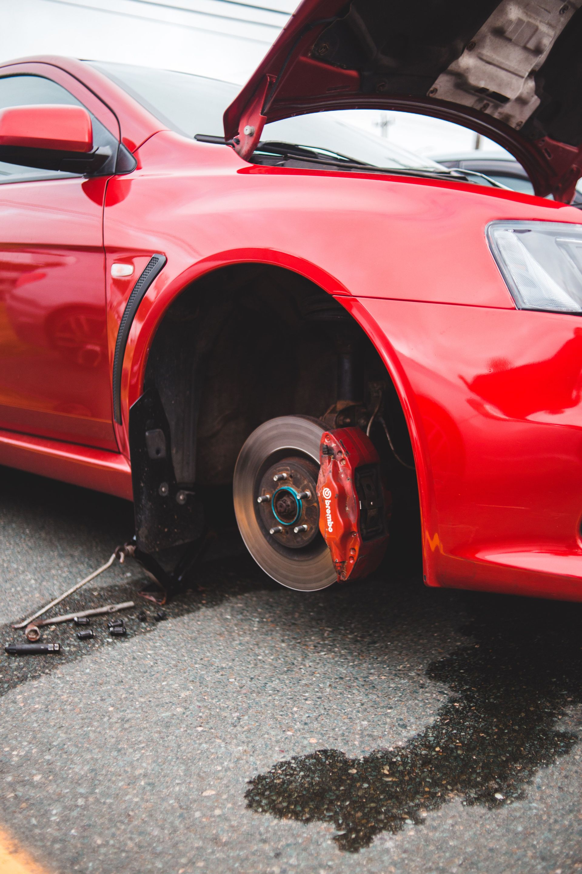 Close-up of a red car with the wheel removed, exposing the brake disc during repair.